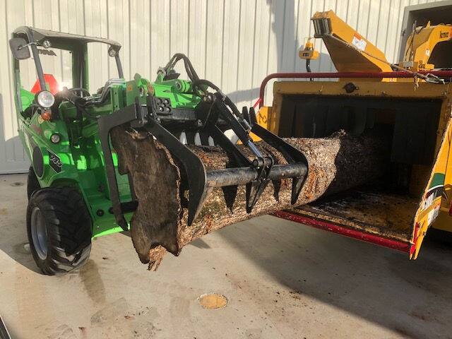 Xtreme Garden Care machinery loading a tree stump into a truck