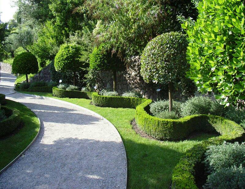 Neatly styled garden with clipped hedges and a paved path